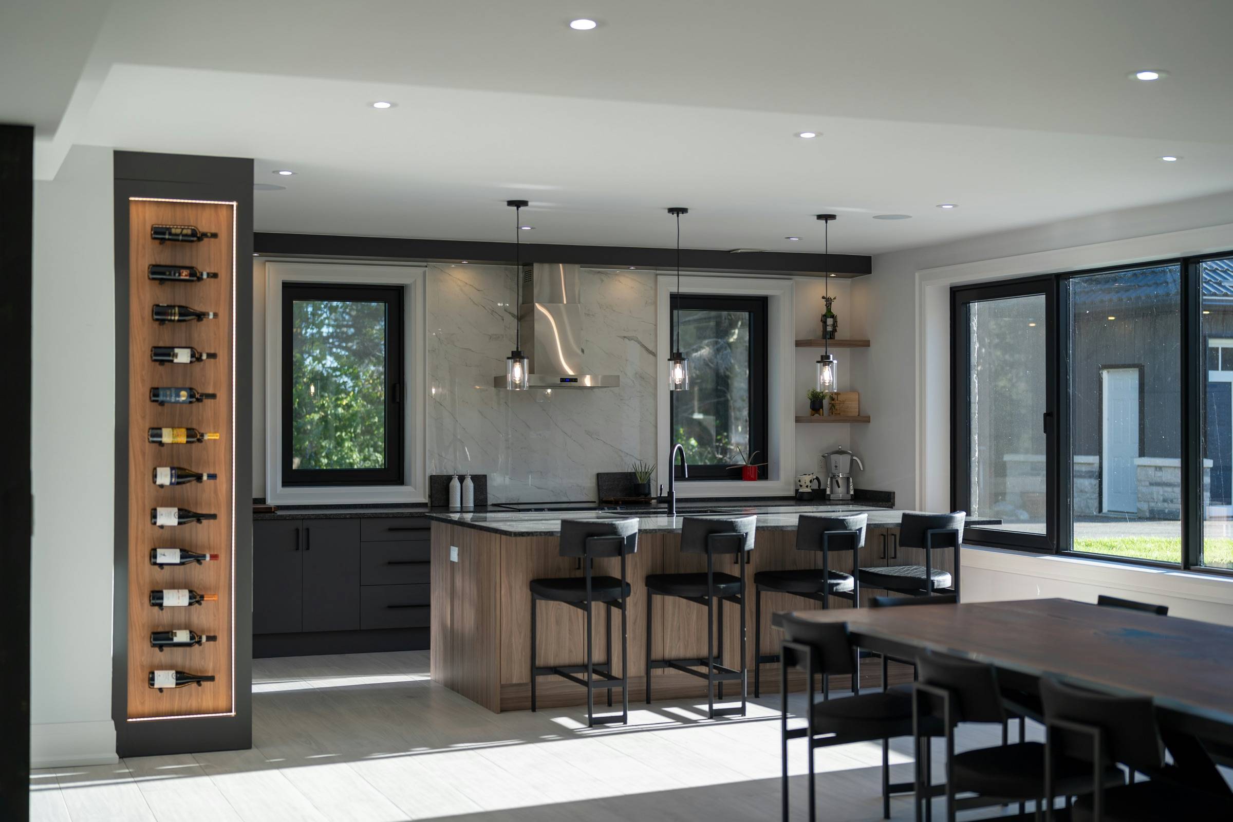Built-in wine wall with label-forward bottle display beside an open modern kitchen and dining area
