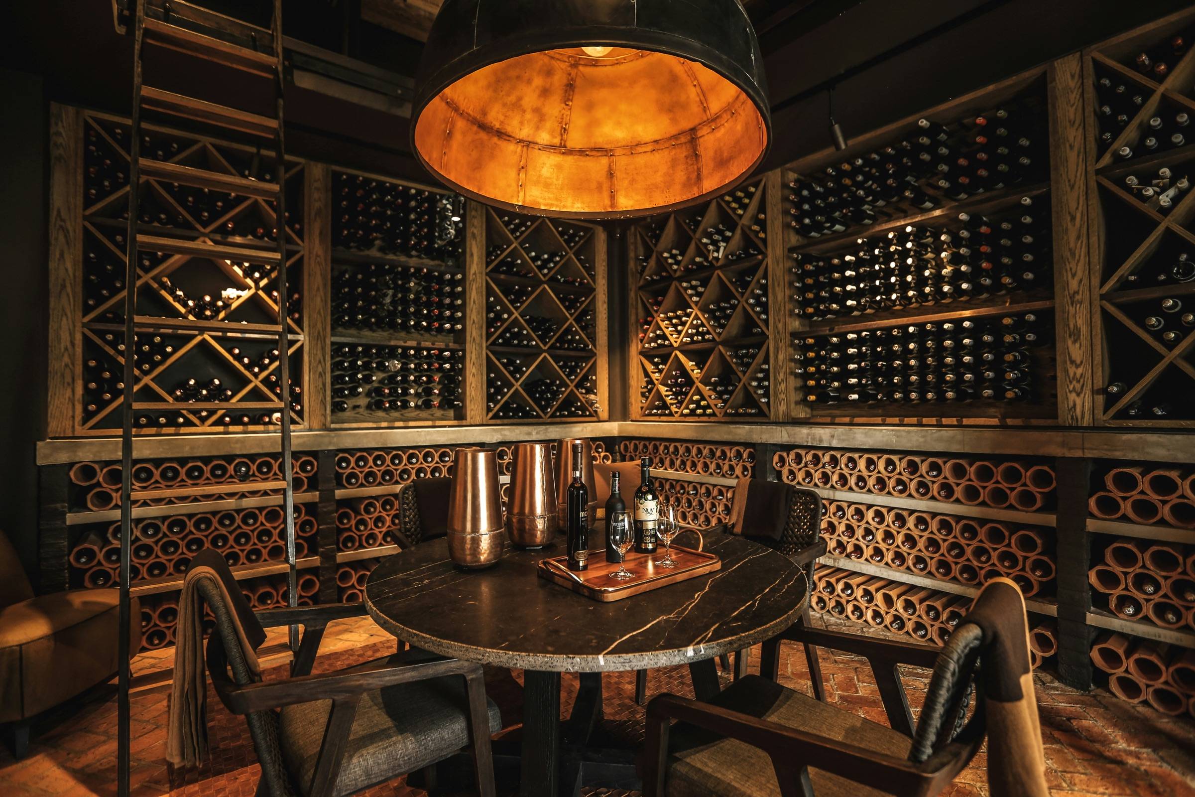 Traditional wine cellar with lattice racking, warm pendant light, and a round tasting table